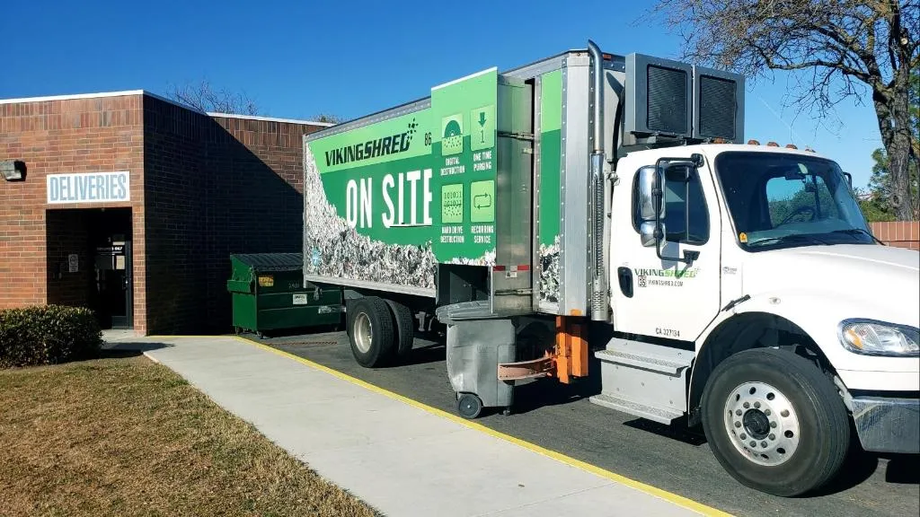 A garbage truck is parked outside a building, showcasing the routine of urban waste disposal services.