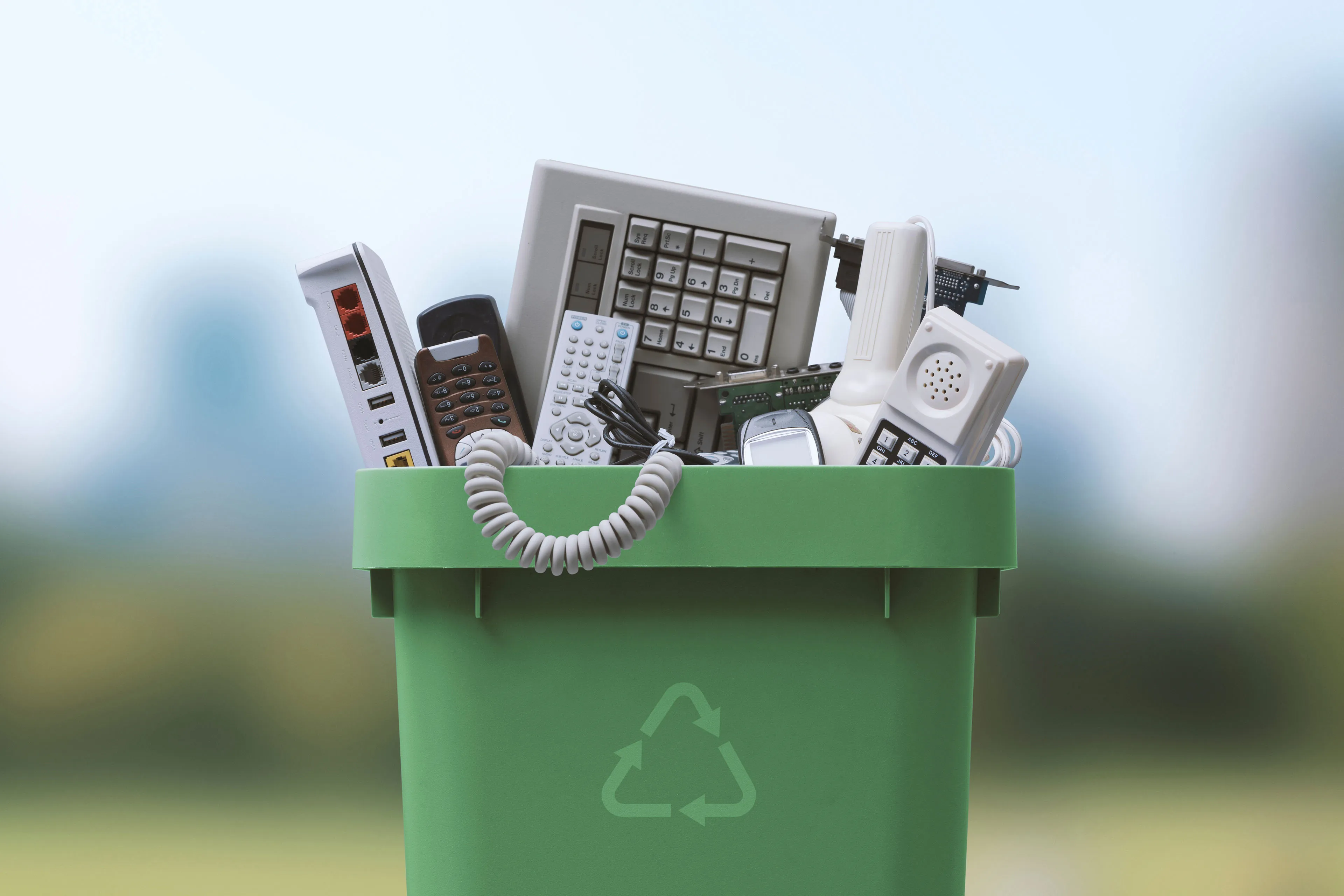 A man wearing a suit is holding a piece of paper near a trash can, contemplating its removal.