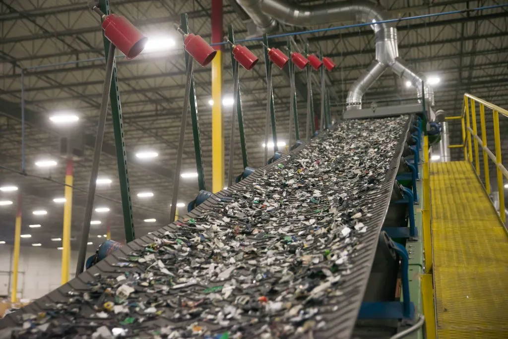 A conveyor belt carrying multiple plastic bottles, showcasing the flow of materials in a processing plant.