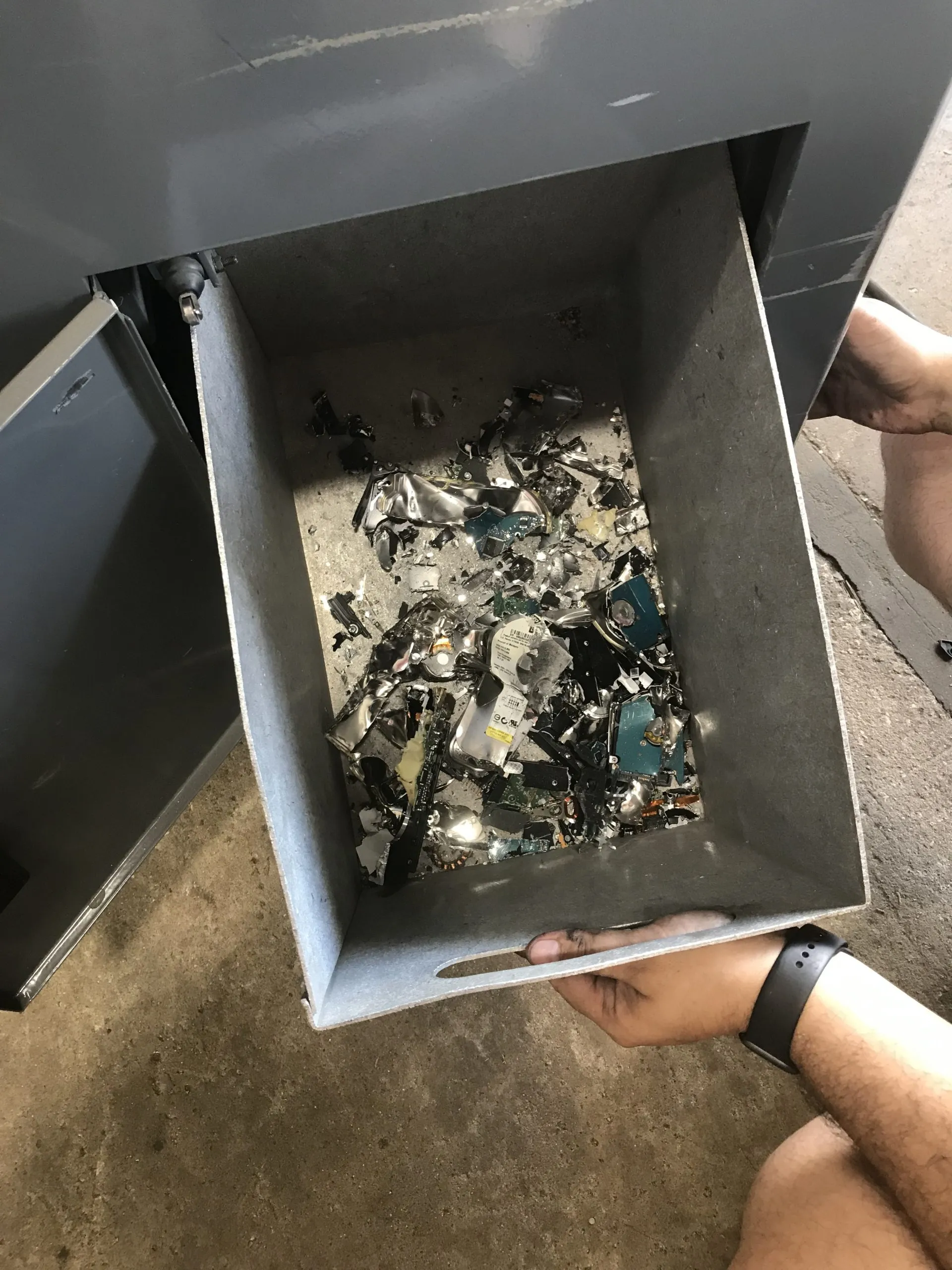 A man is inspecting a metal box as he opens it, discovering numerous metal pieces inside.