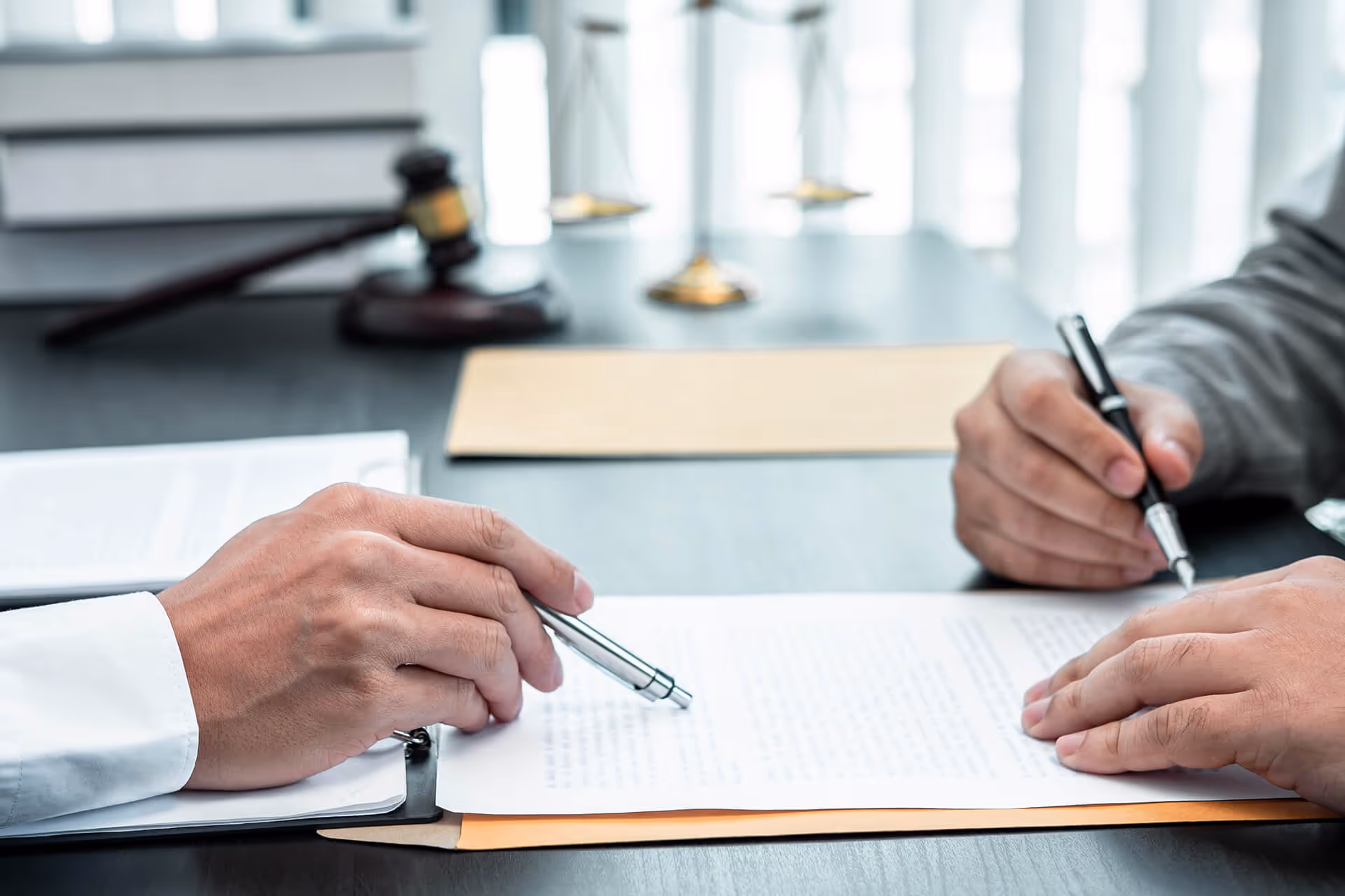 Male lawyer discussing a legal document with a client in an office featuring a gavel and scales of justice