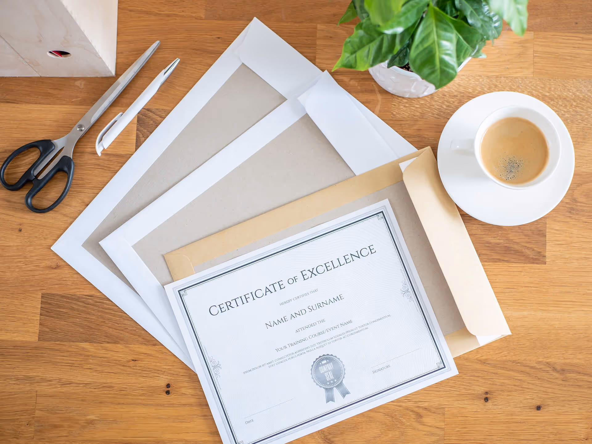 A formal Certificate of Excellence inside a heavy paper envelope on a wooden desk with office supplies and coffee