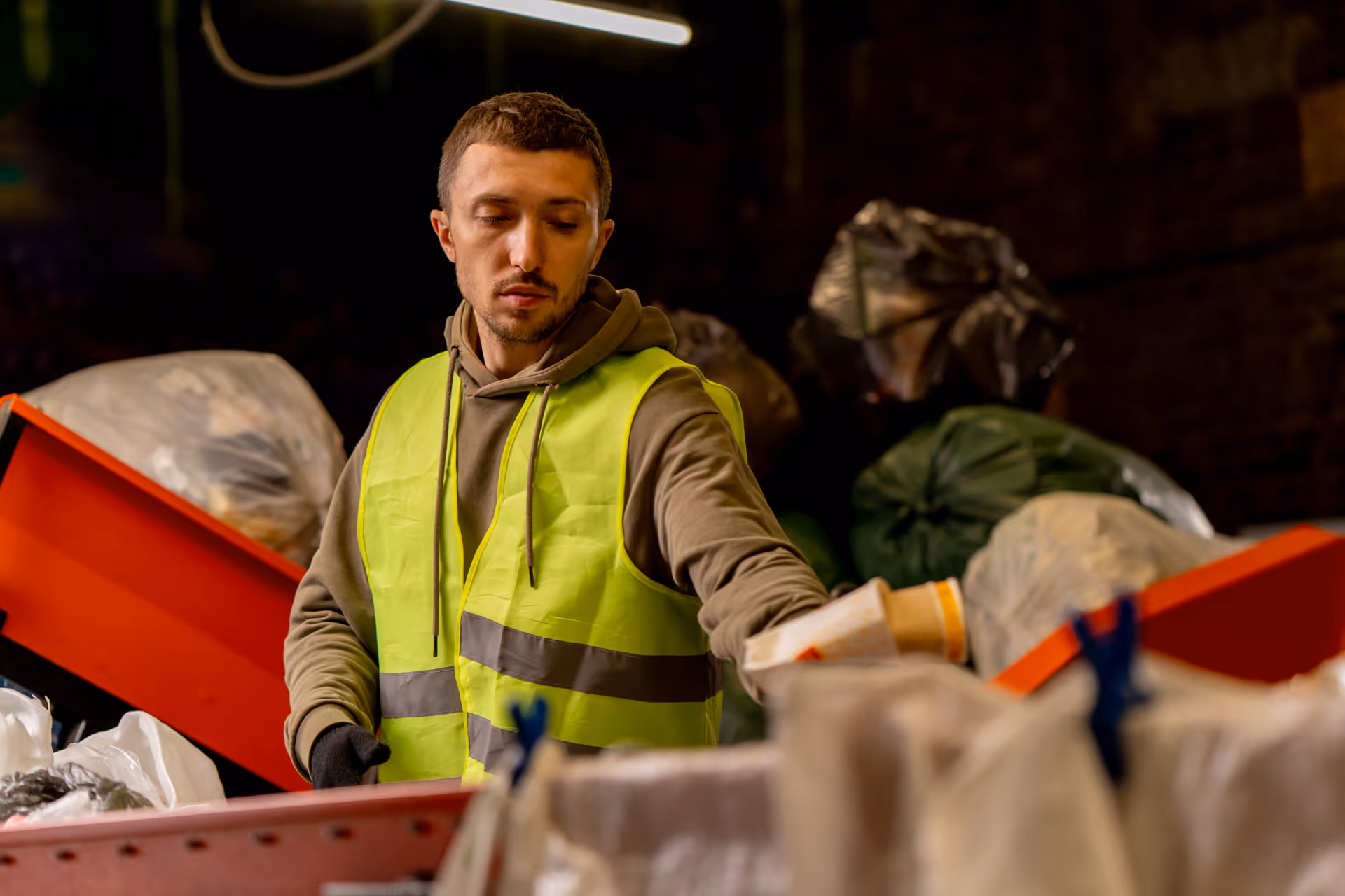 Waste management worker in a high-visibility vest sorting recyclables at a facility