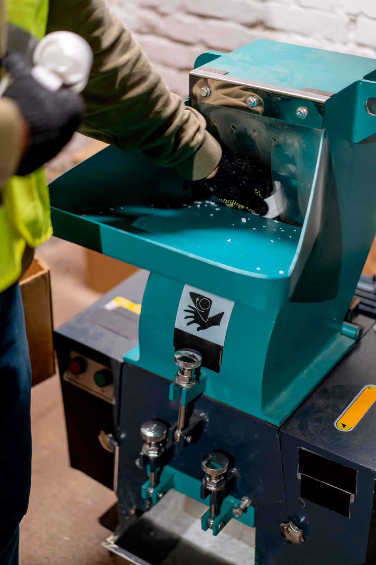 Industrial plastic shredder being operated by a worker in safety gloves