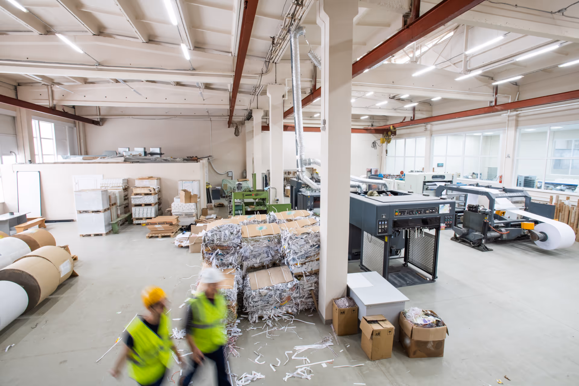 Industrial paper recycling facility with workers, paper rolls, and baled shredded paper