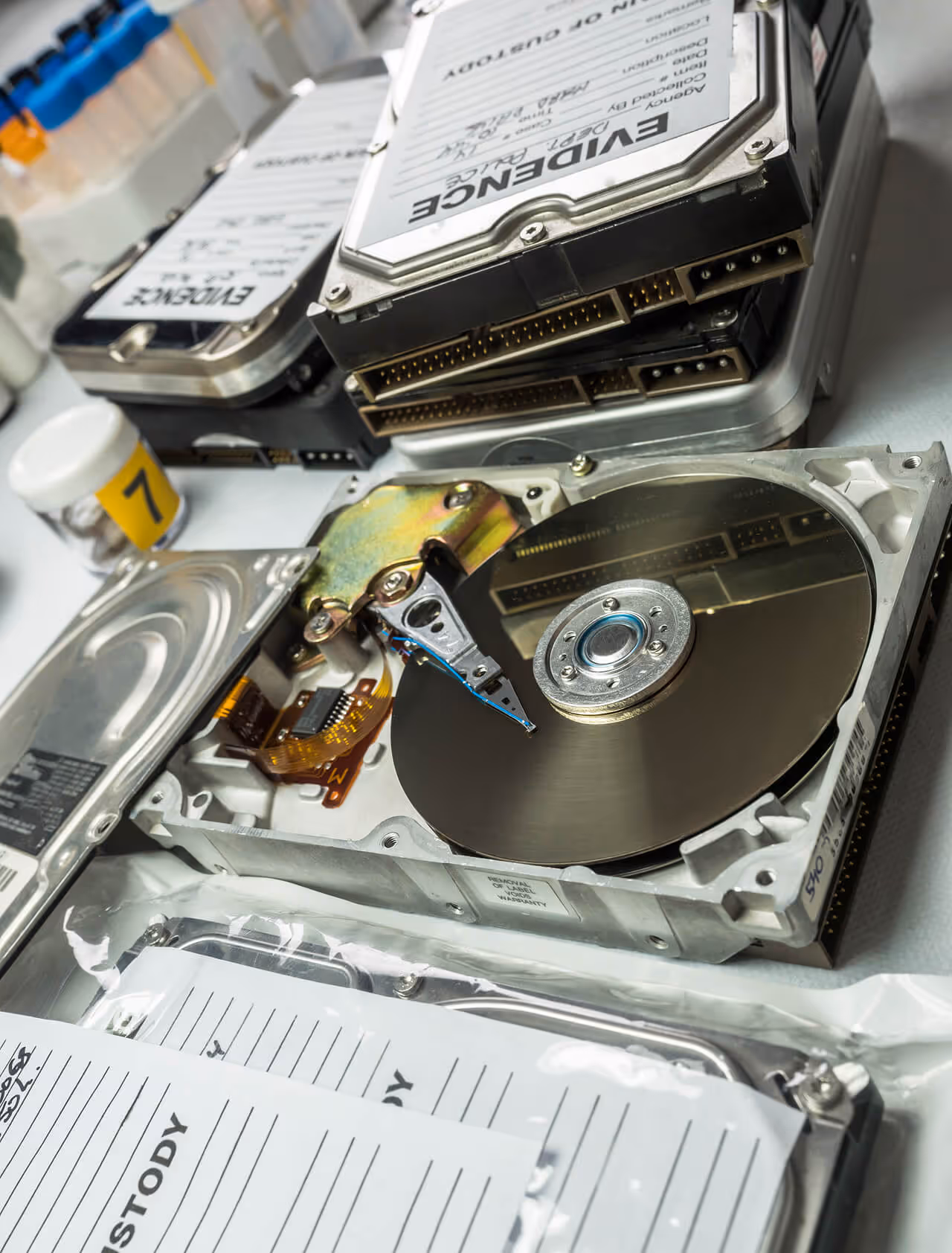 Open hard drive and evidence-labeled disks in a digital forensics lab