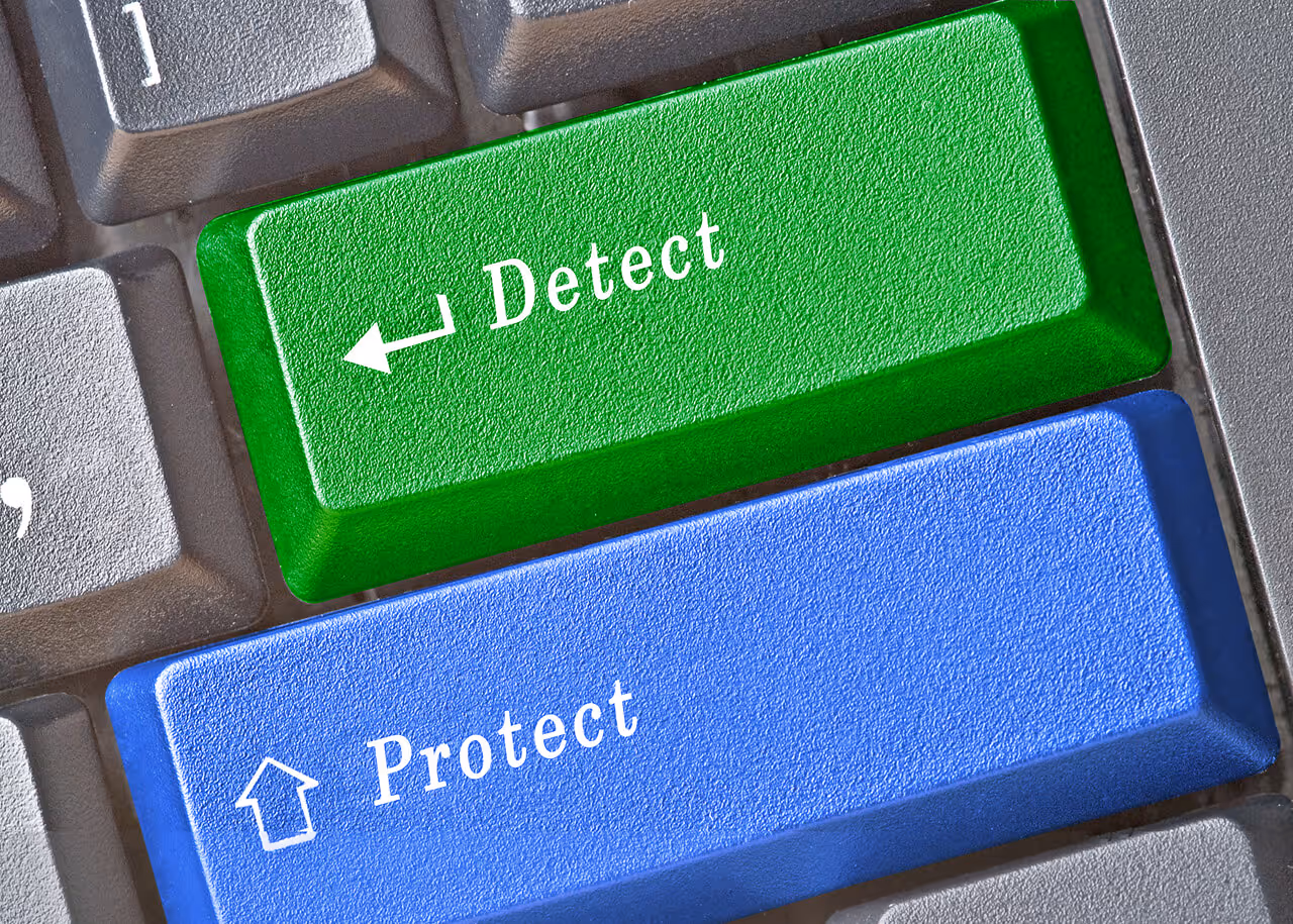 Close-up of a computer keyboard featuring a green "Detect" key and a blue "Protect" key for cybersecurity and data safety