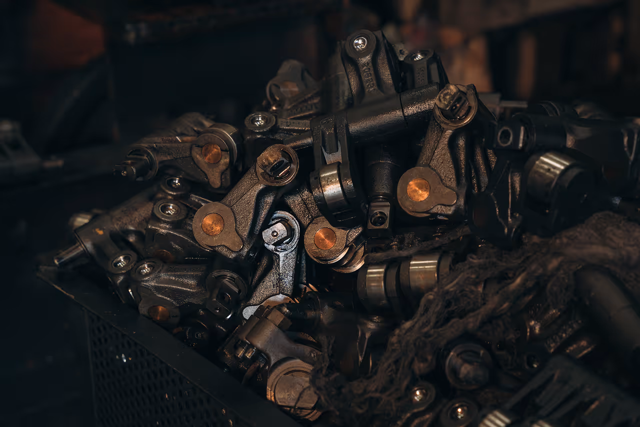 Pile of heavy-duty black metal mechanical components and engine parts in a storage bin