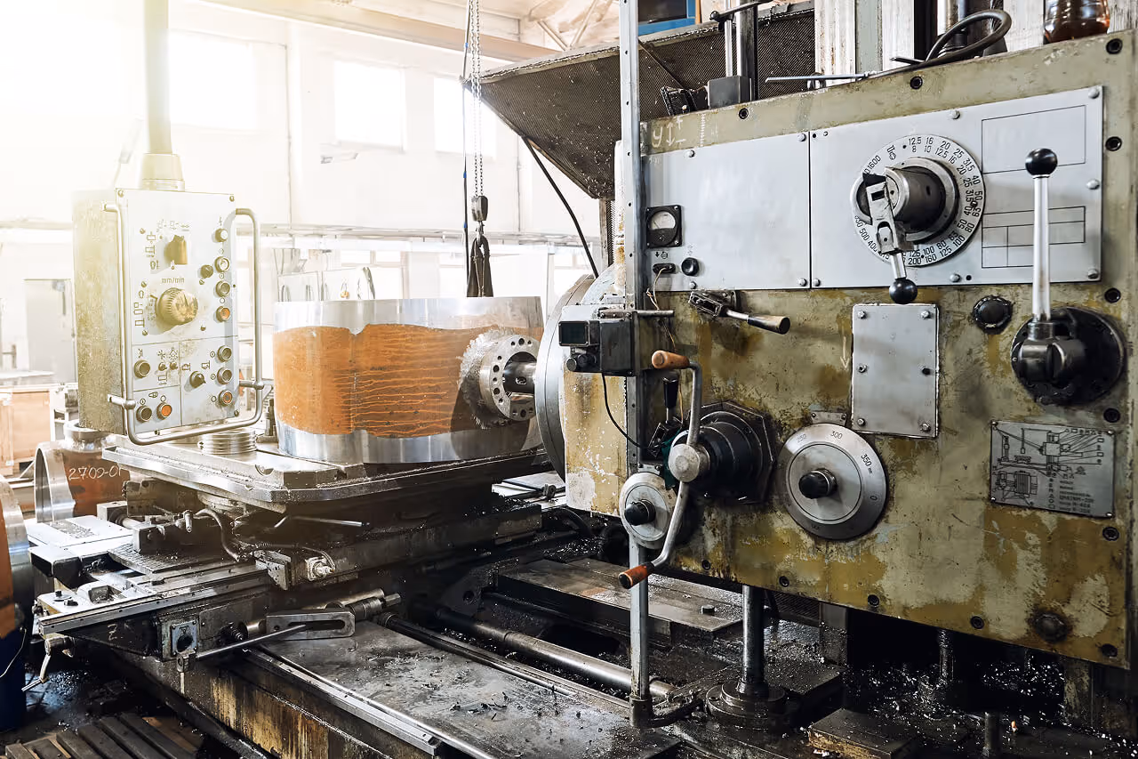 Heavy-duty industrial lathe machine processing a large cylindrical metal component in a factory