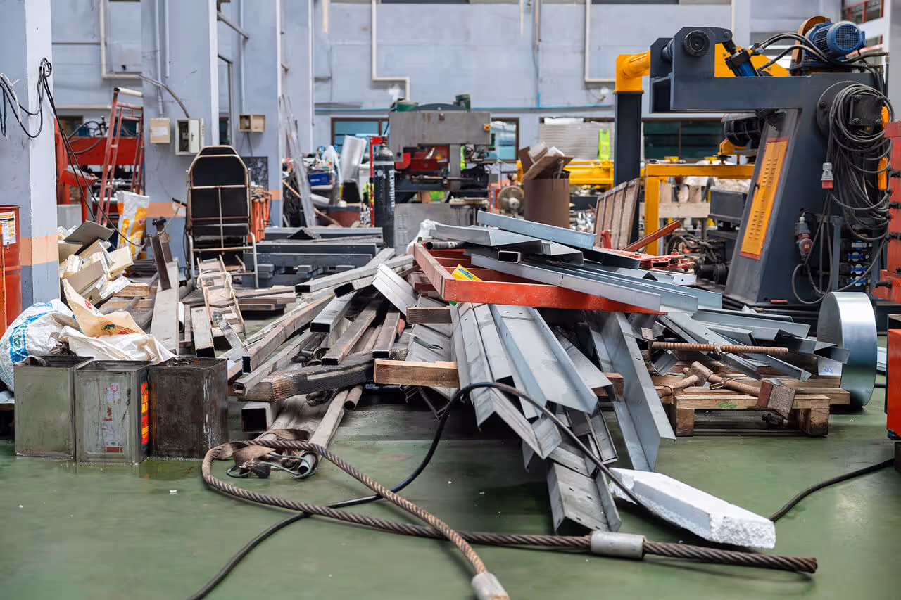 Scrap metal beams and industrial materials piled on the floor of a manufacturing facility